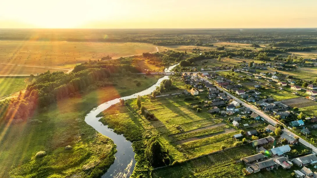 Naturnah wohnen und bauen in Beeskow Luftaufnahme einer ländlichen Region mit Fluss, Feldern und Wohngebiet als Symbol für Hausbau in Königs Wusterhausen