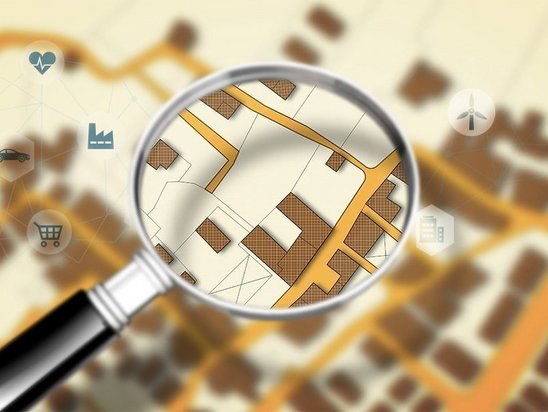 Lupe über einem Lageplan als Symbol für Grundstückssuche und Hausbau in Mühlenfließ